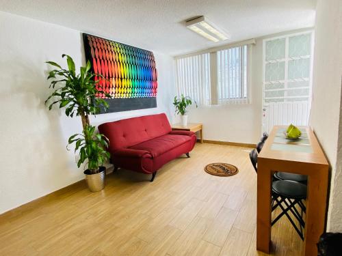 uma sala de estar com um sofá vermelho e uma pintura na parede em Cómodo y Pintoresco Depa Al sur de La Ciudad! em León