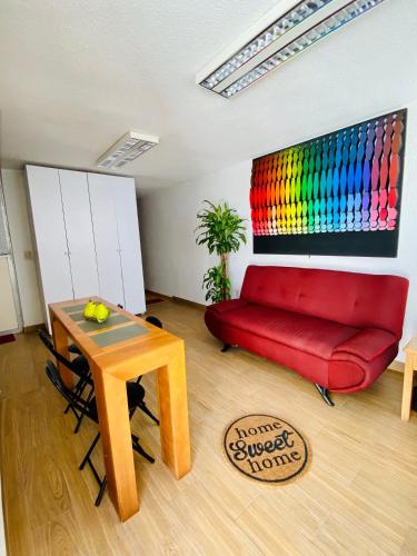 a living room with a red couch and a table at Cómodo y Pintoresco Depa Al sur de La Ciudad! in León