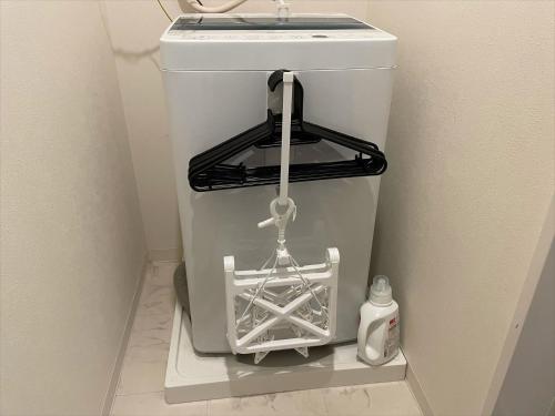 a white trash can in a corner of a bathroom at COTO Tokyo Shibuya 8 in Tokyo