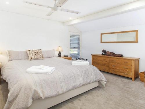 a white bedroom with a large bed and a dresser at Aroona at Minnamurra in Minnamurra