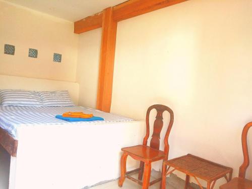 1 dormitorio con 1 cama y 2 sillas de madera en Lazy Bones, en Koh Rong Sanloem