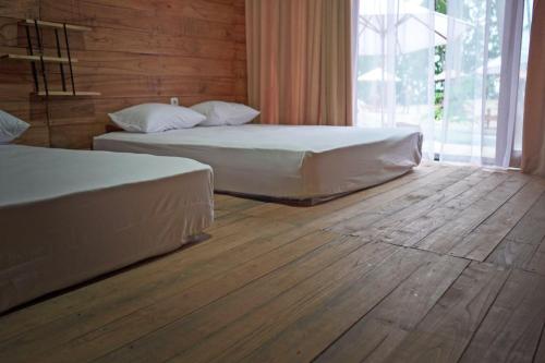 2 camas en un dormitorio con suelo de madera en Pulau Mahitam Resort & Cottage by Hotelku, en Ratai