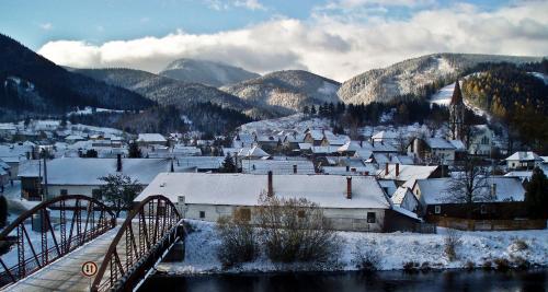 a small town with snow covered buildings and a bridge at Útulný dovolenkový dom in Liptovský Hrádok