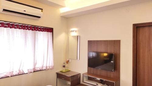 a room with a flat screen tv and a window at Hotel Rhythm Grand Suite in Tiruchchirāppalli