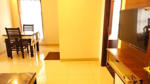 a living room with a dining table and a flat screen tv at Hotel Rhythm Grand Suite in Tiruchchirāppalli
