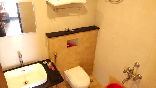 a bathroom with a white toilet and a sink at Hotel Rhythm Grand Suite in Tiruchchirāppalli