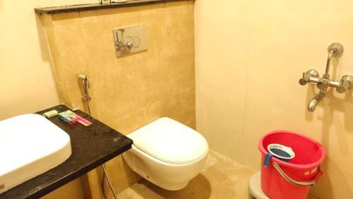 a bathroom with a toilet and a sink and a red bucket at Hotel Rhythm Grand Suite in Tiruchchirāppalli