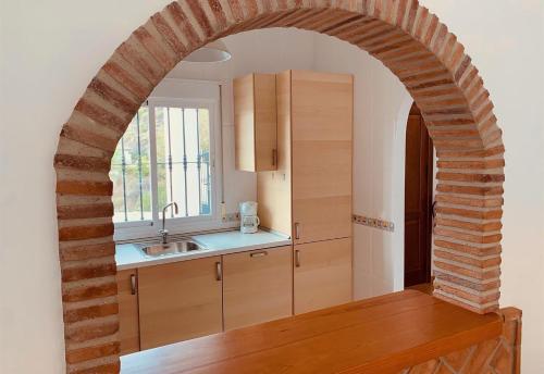 un arco en una cocina con fregadero y barra en Casa Verdejo en Cómpeta
