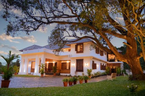 a white house with a tree in the yard at Surya Heritage Hotels in Kannur