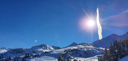a jet trails in the sky over a snow covered mountain at RESIDENCE LE PACHA Courchevel 1850 in Courchevel