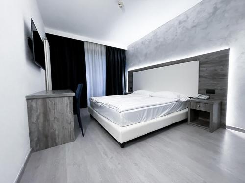 a bedroom with a white bed and a desk and a bed sidx sidx sidx sidx at Hotel De Nac in Nago-Torbole