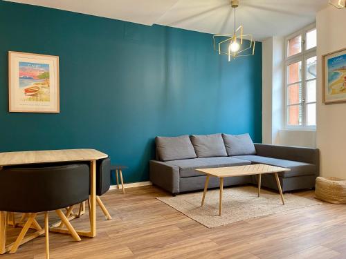 a living room with a couch and a blue wall at République - Grande la Réal in Perpignan
