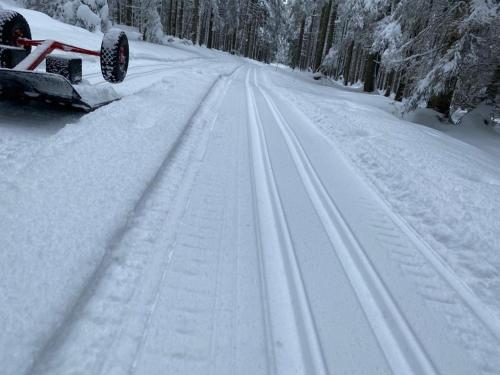 a snow covered road with tire tracks in the snow at Penzion Panský dům in Kvilda