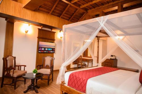a bedroom with a canopy bed and a table and chairs at Surya Heritage Hotels in Kannur
