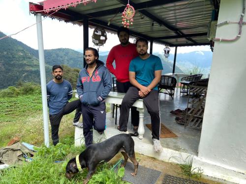 a group of men sitting on a table with a dog at Dhanaulti Camp Homes Retreat in Dhanaulti