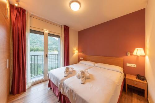 a hotel room with a bed and a large window at Apartaments Trainera in Esterri d'Àneu