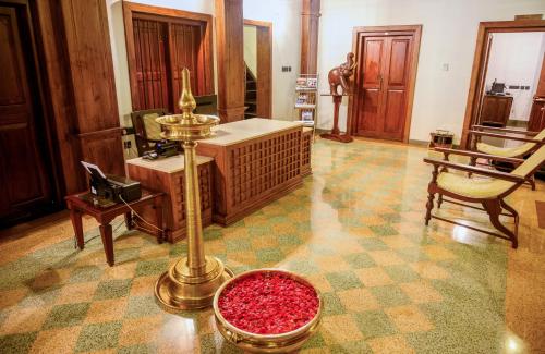 a living room with a desk and a table with a bowl of red pills at Surya Heritage Hotels in Kannur