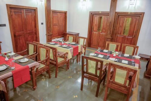 a dining room with wooden tables and chairs at Surya Heritage Hotels in Kannur
