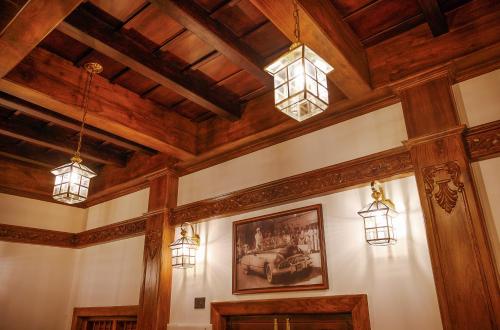 a room with wooden ceilings and lights and a painting at Surya Heritage Hotels in Kannur
