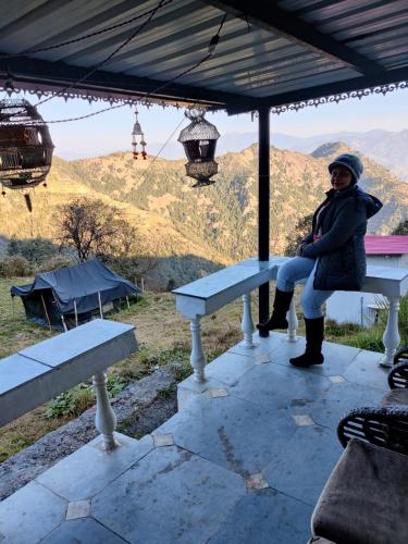 a woman sitting on a bench under an umbrella at Dhanaulti Camp Homes Retreat in Dhanaulti