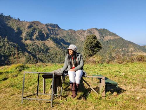 a woman sitting on a table in a field at Dhanaulti Camp Homes Retreat in Dhanaulti