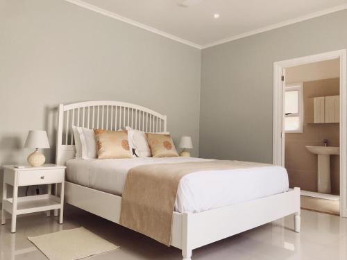 a white bedroom with a white bed and a mirror at Panorama Guesthouse Apartments Beau Vallon Beach in Beau Vallon