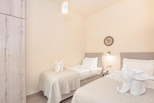 a bedroom with two beds and a clock on the wall at Seaview Apartment SUNRISE Near To Falassarna Beach in Kolymvari