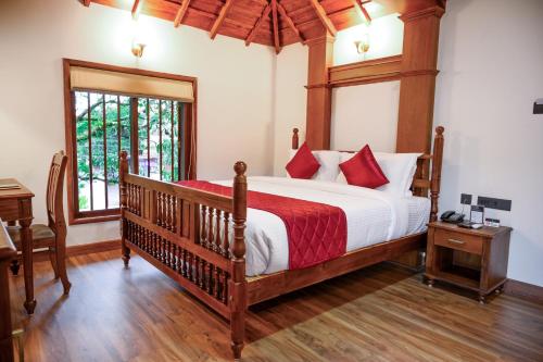 a bedroom with a large bed with red pillows at Surya Heritage Hotels in Kannur