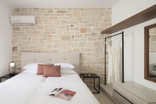 a bedroom with a white bed and a brick wall at Evaero Villas I, II, III, IV, Family Retreats, By ThinkVilla in Sfakaki