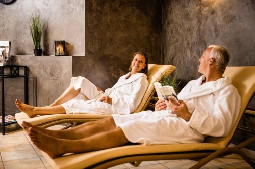 a man and woman sitting in chairs in a room at Wirthshof Hotel & Chalets in Markdorf
