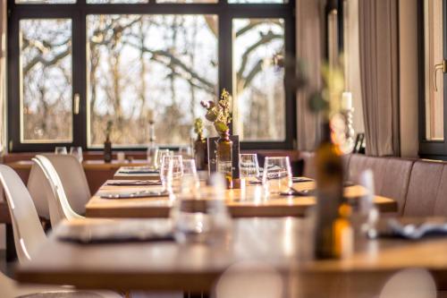 a restaurant with wooden tables and chairs and windows at Wirthshof Hotel & Chalets in Markdorf