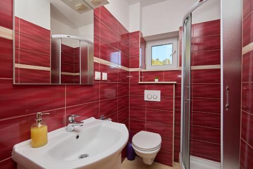 a red bathroom with a sink and a toilet at Apartments BARO in Maranovići