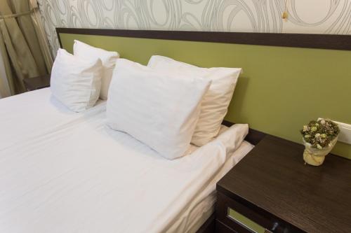 a bedroom with a bed with white pillows and a table at Hotel Voyage in Kharkiv