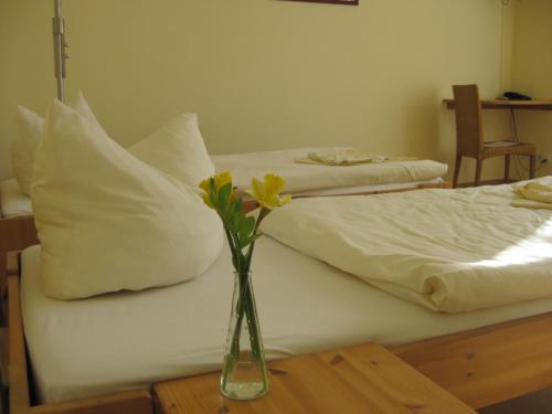 a vase with flowers on a table next to a bed at Doppelzimmer Gästehaus Mühlenstein in Bad Sülze