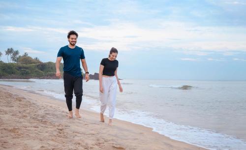 a man and a woman walking on the beach at Surya Heritage Hotels in Kannur