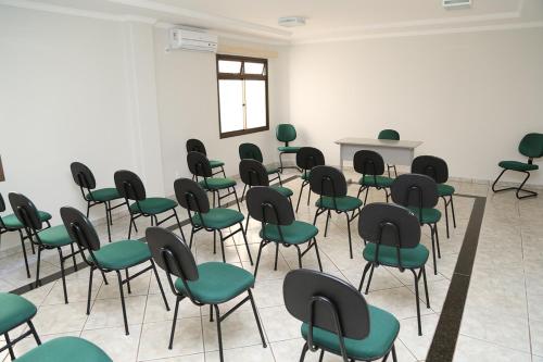 an empty room with green chairs and a table at Big Executive Hotel in Araguari
