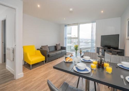 a living room with a table and a yellow chair at Dream Apartments Belfast in Belfast