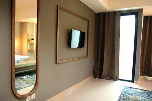 a bathroom with a mirror and a television on the wall at StayG Eastern Green by GranDhika - Bekasi in Padurenan