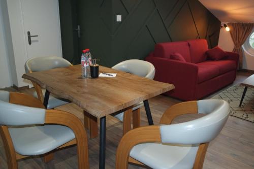a dining room with a table and a red couch at Logement de La Sittelle in Aizenay