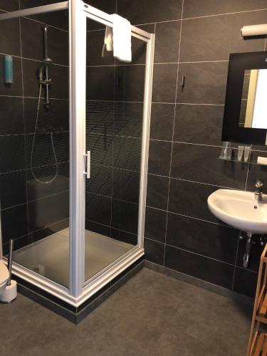 a shower with a glass door next to a sink at Hotel Oude Abdij in Lo-Reninge