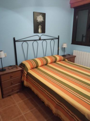 1 dormitorio con 1 cama con un colorido edredón a rayas en Casa Rural Blascosancho, en Blascosancho