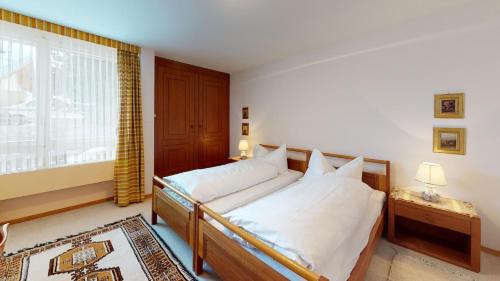 a bedroom with a bed with white sheets and a window at St Moritzerhof 62 in St. Moritz