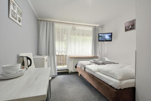 a bedroom with a bed and a table and a television at 4 Pory Roku in Karpacz