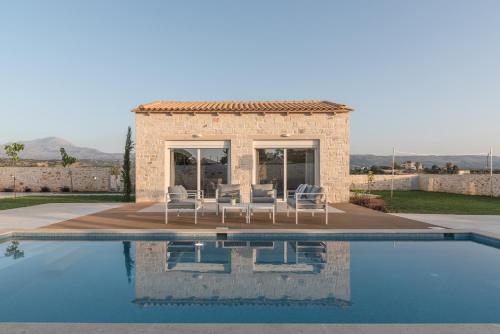 a villa with a swimming pool and a house at Evaero Villas I, II, III, IV, Family Retreats, By ThinkVilla in Sfakaki