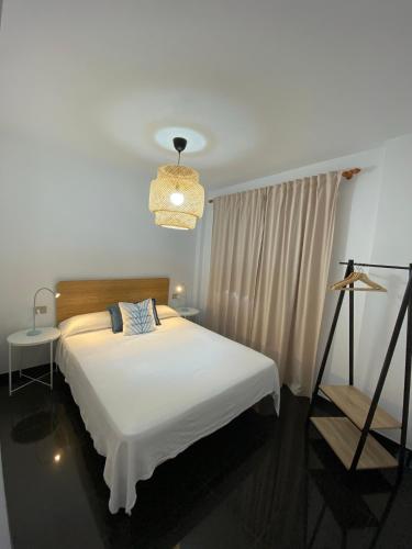a bedroom with a white bed and a chandelier at Los Zifios in La Restinga