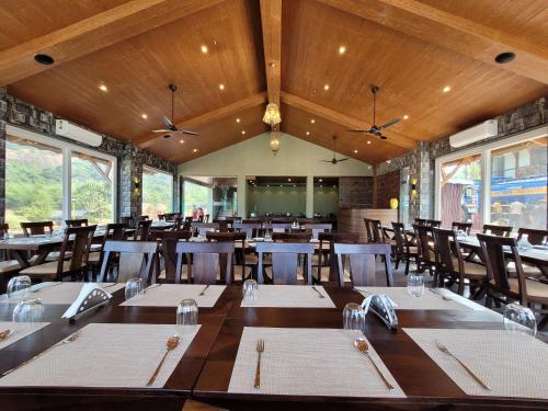 una sala da pranzo con tavoli, sedie e finestre di Mastiff Grand La Villae a Lonavala