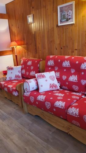 - un canapé rouge avec des oreillers rouges et blancs dans l'établissement Front de Neige Isola 2000, à Isola 2000