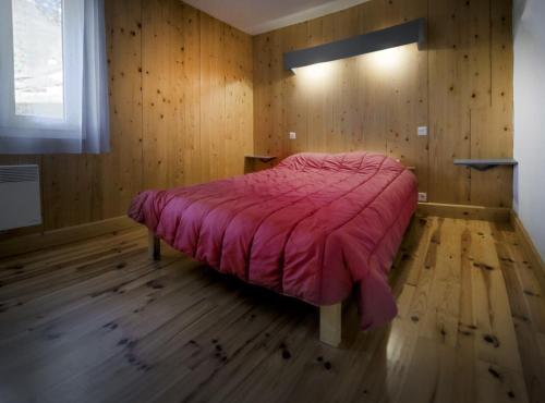 a bedroom with a bed with a pink comforter at Village de Gites le Colombier in Mende
