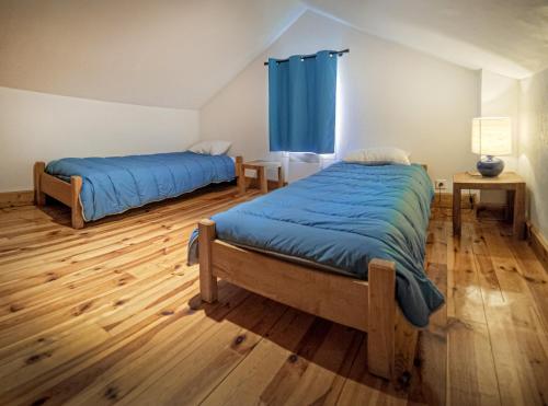 a bedroom with two beds and a blue curtain at Village de Gites le Colombier in Mende