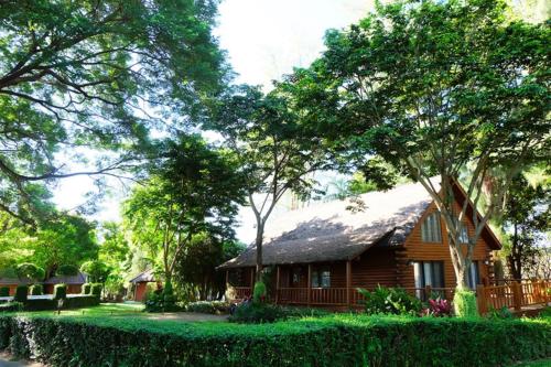a wooden house with a thatched roof in a park at Felix River Kwai Resort - SHA Plus,Certified in Kanchanaburi